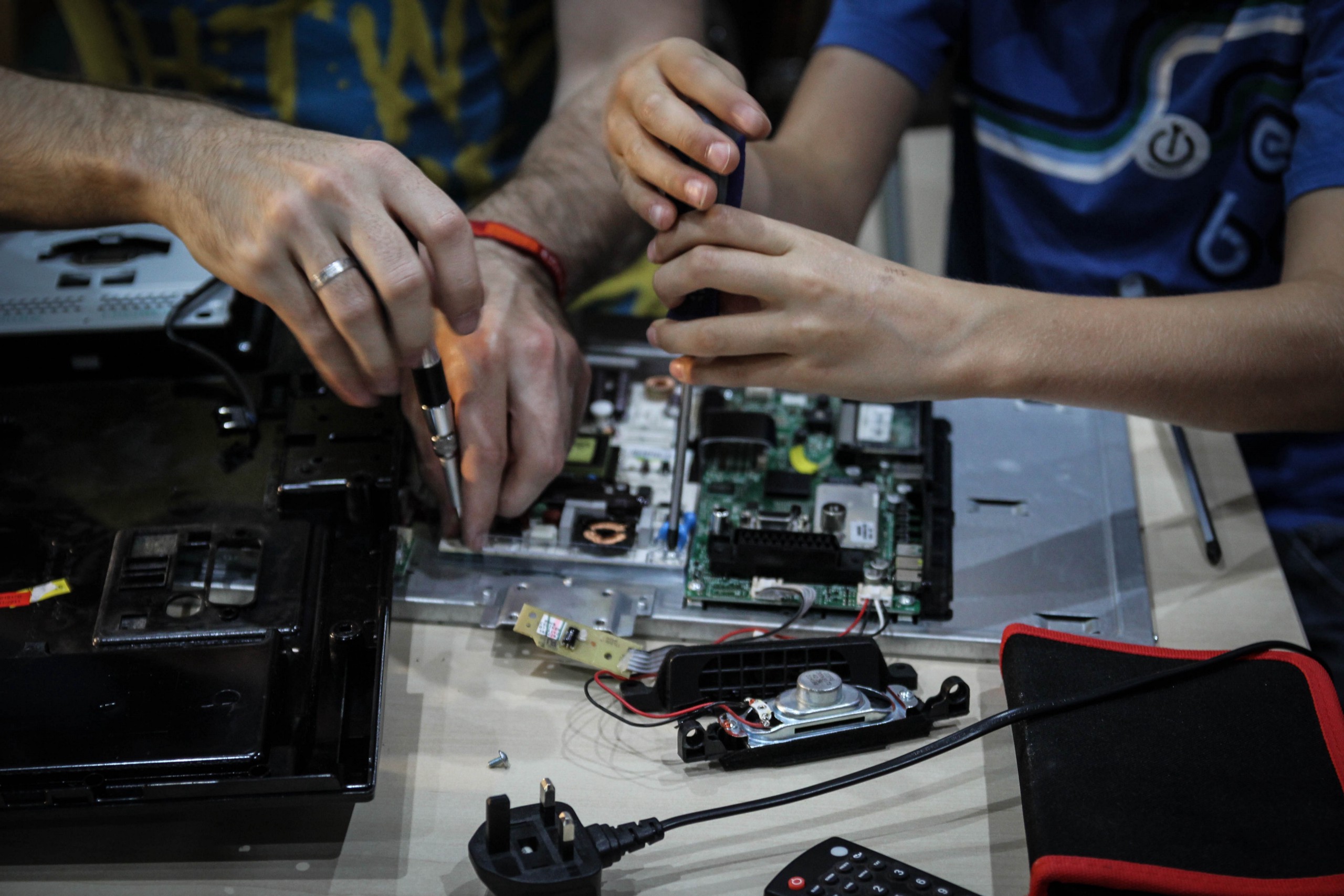 A pair of hands repairing circuit boards with tools.