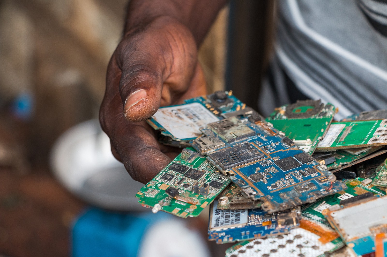 A hand holds a number of used circuit boards from broken phones.