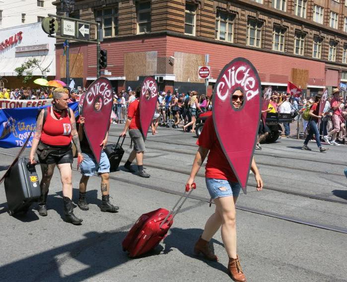 A group of protesters walk along a street wearing costumes.