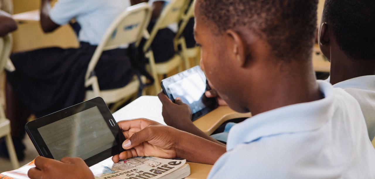 A child holds a tablet computer in a classroom.